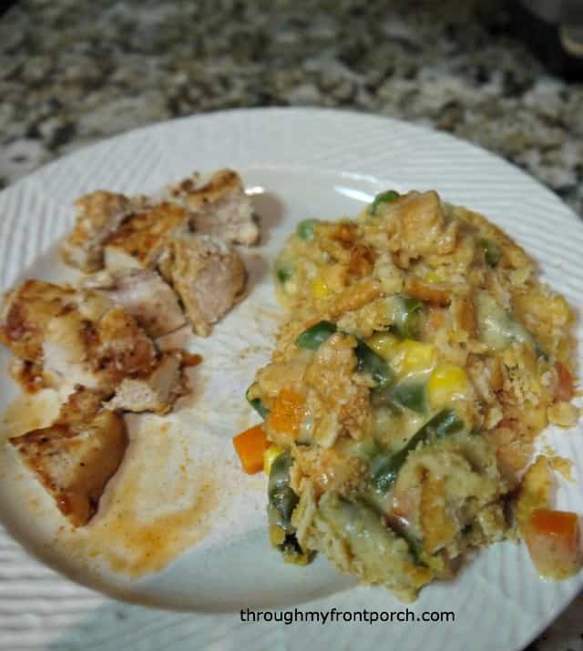 Cheesy vegetable casserole on a plate with pieces of chicken.