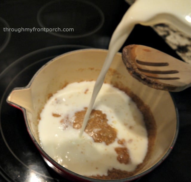 Pouring milk into a roux in a saucepan.