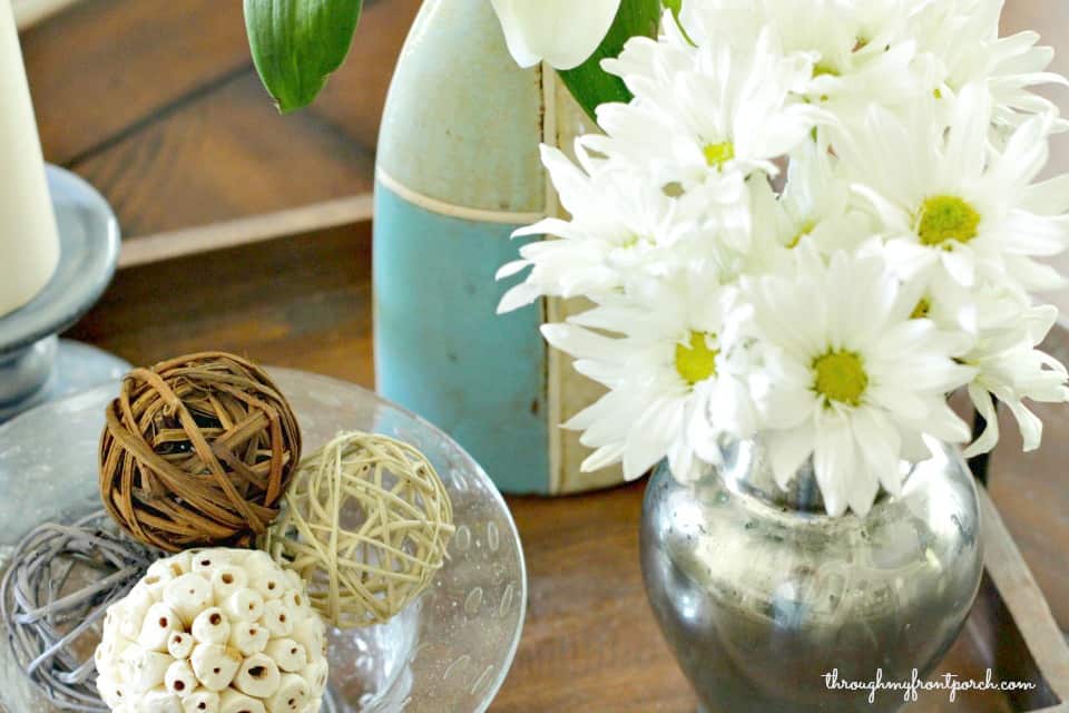 Flowers in vase next to spheres in a bowl.