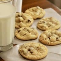 Chocolate chip cookies with a glass of milk on table.