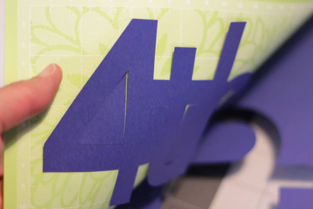 Lifting the cut paper image from the mat.