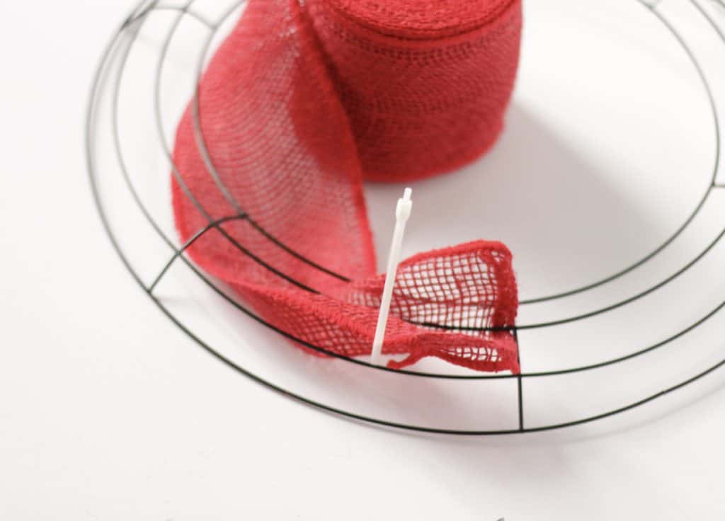 Adding ribbon to a wreath form with a zip tie.