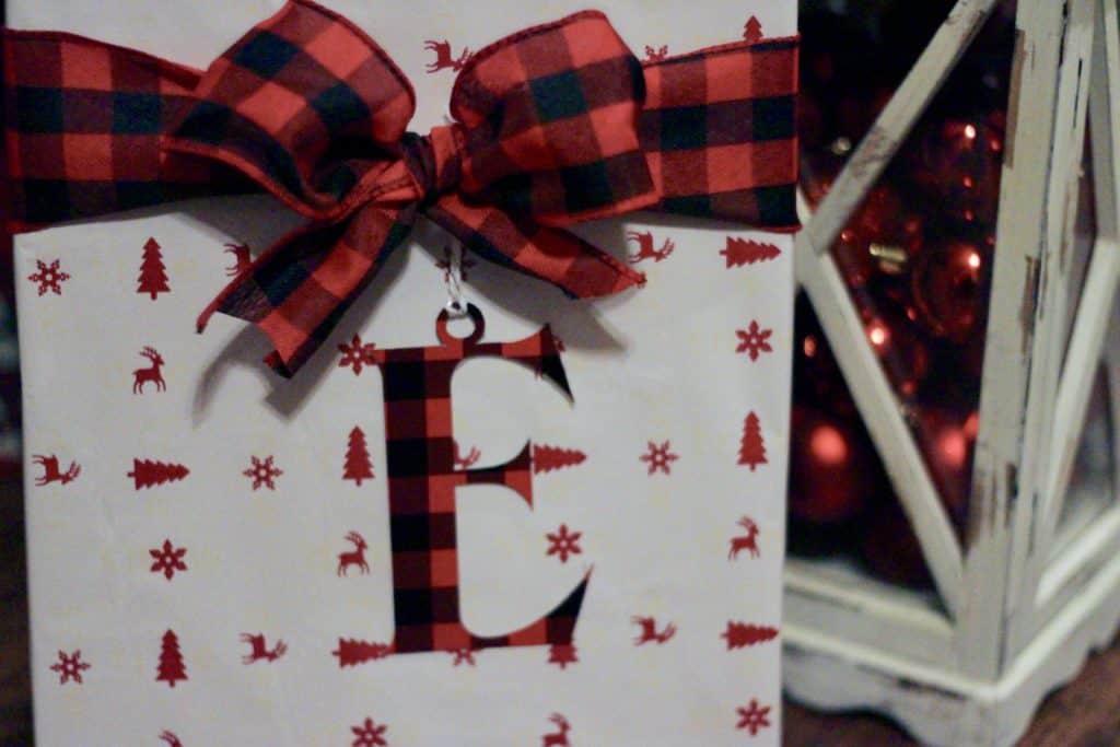 A present with a bow and a letter E monogram on it with a lantern full of ornaments.