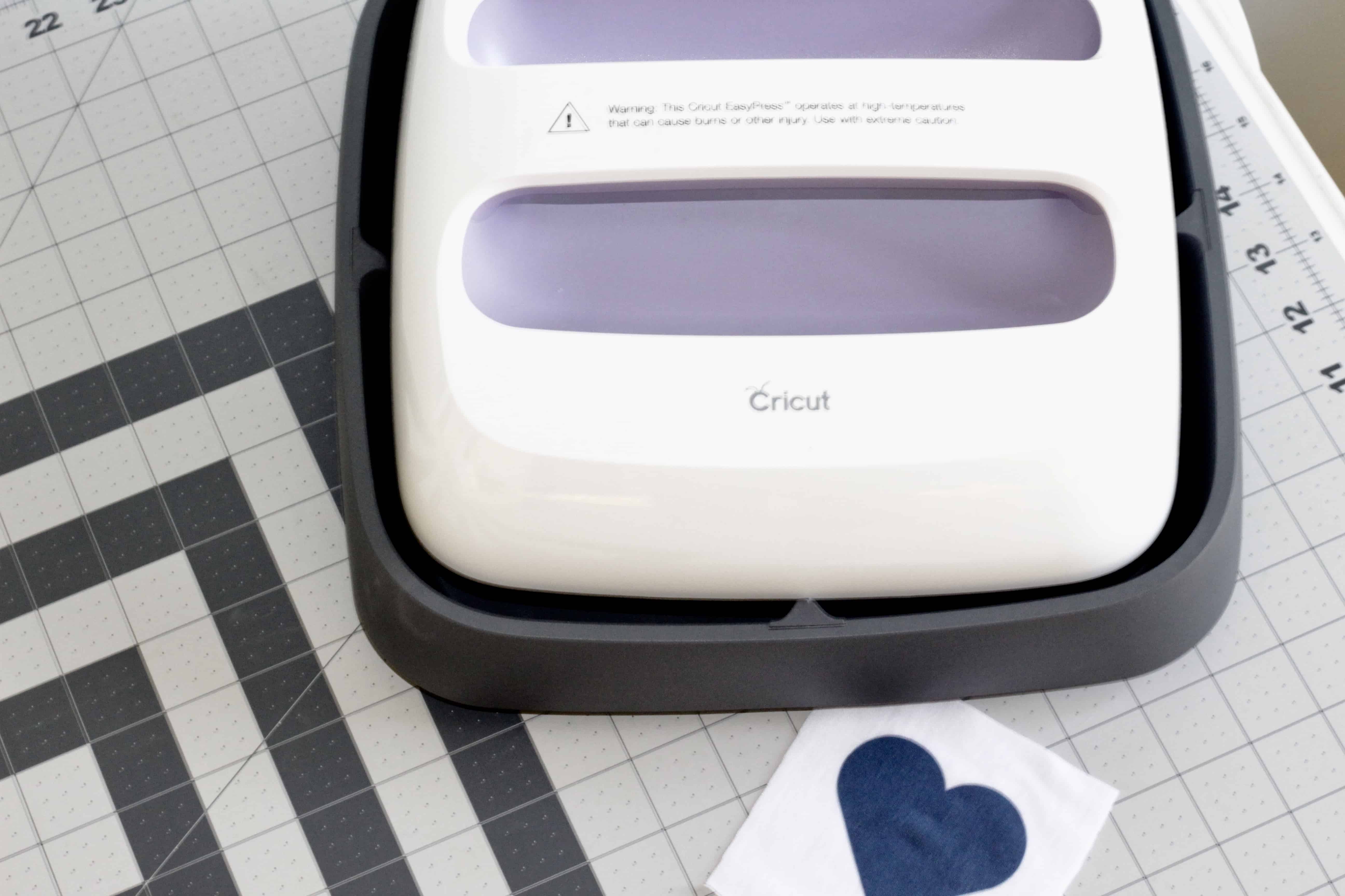Cricut EasyPress with a heart on a fabric square.