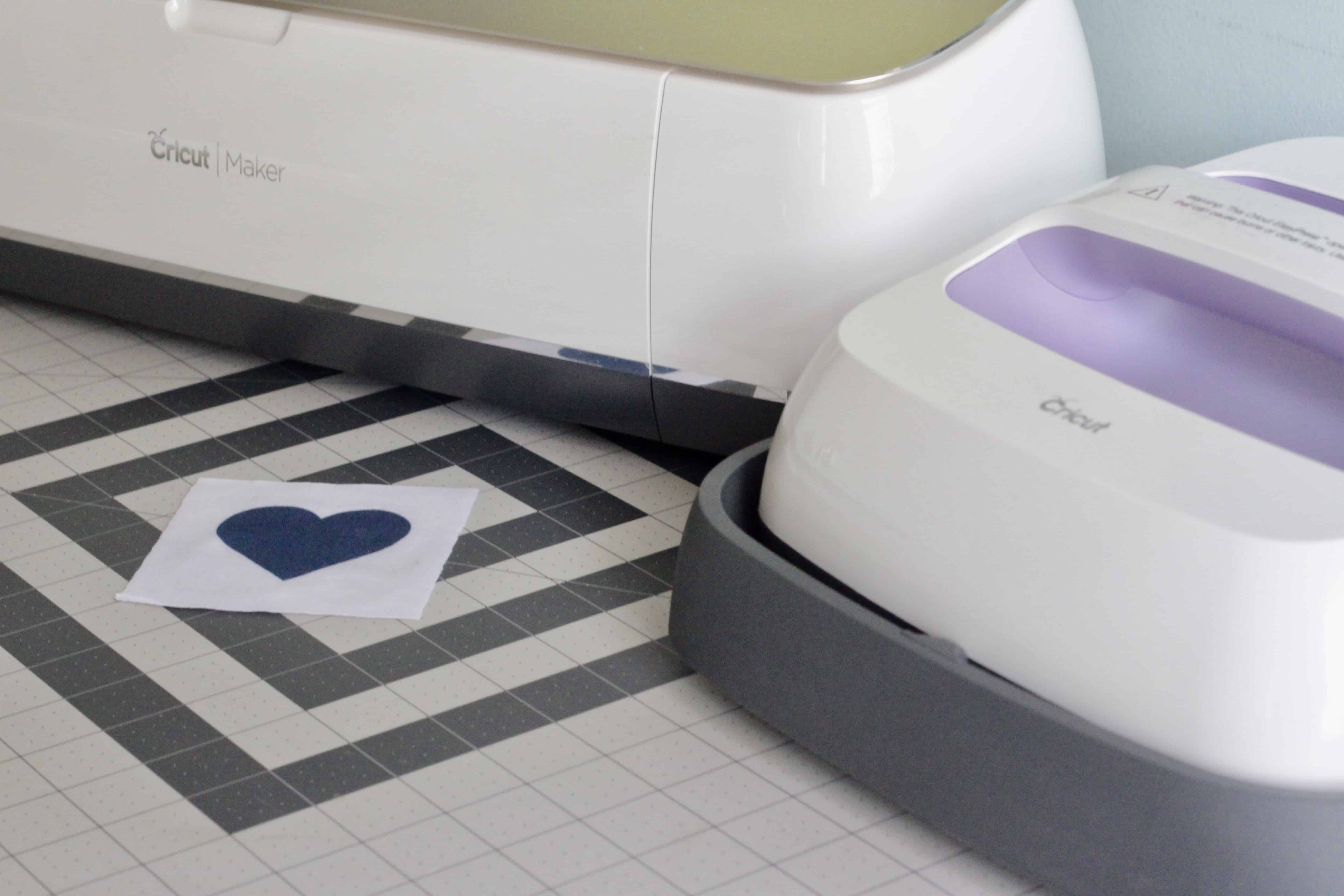 A Cricut Maker with a Cricut EasyPress on a table.