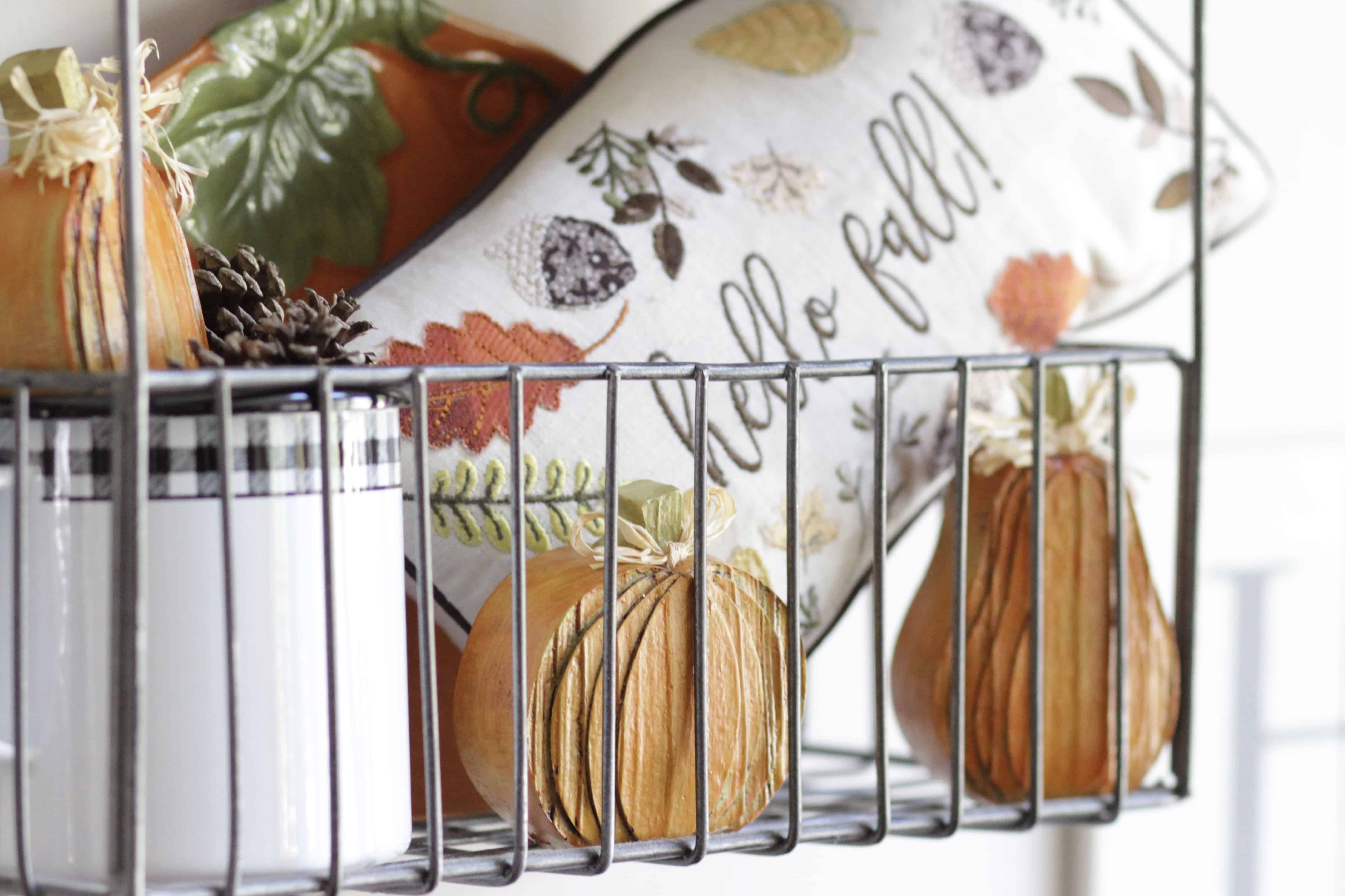 A closeup of hello fall pillow and mug with small wooden pumpkins.