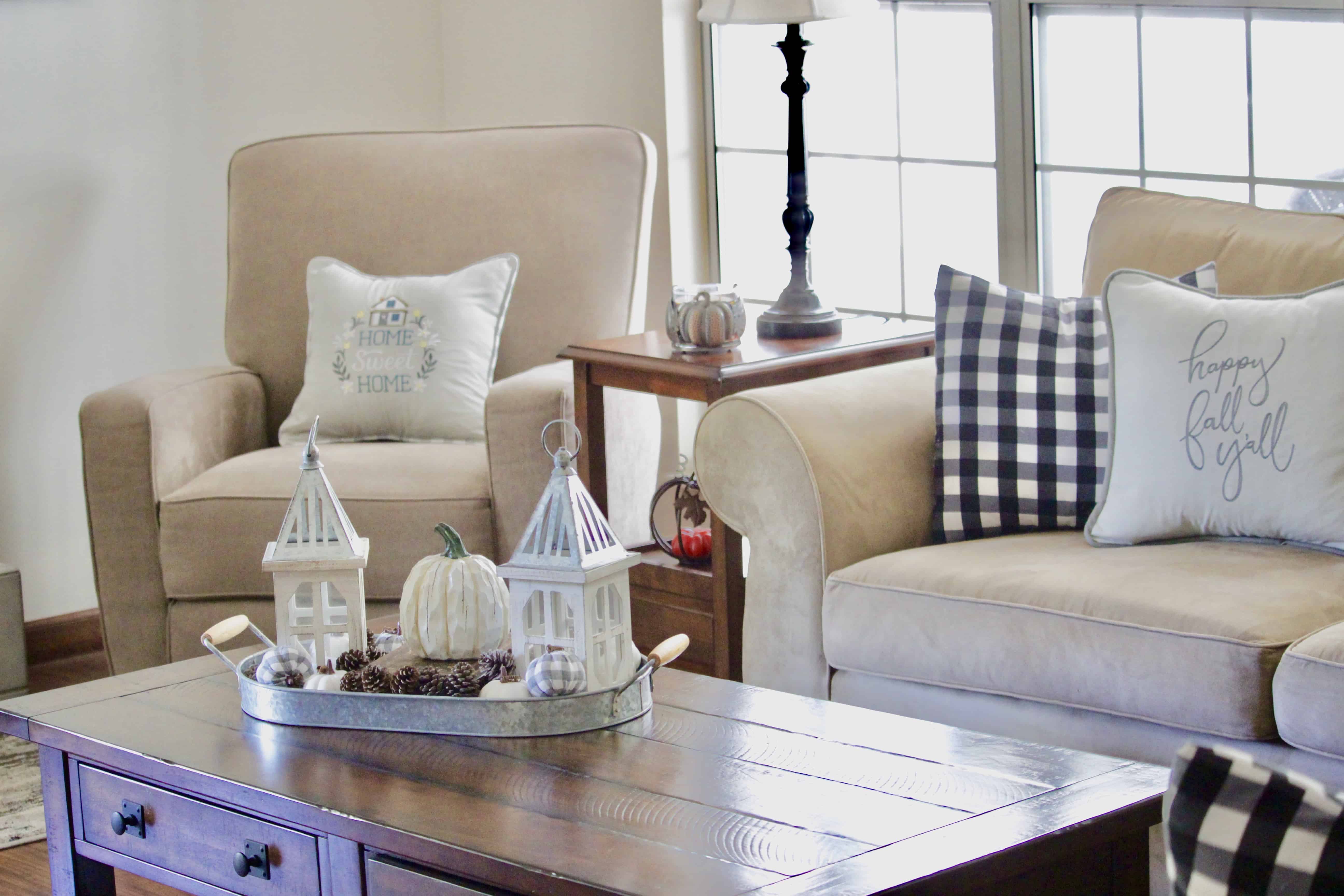 A chair and sofa with a tray of fall decor sitting on a coffee table.