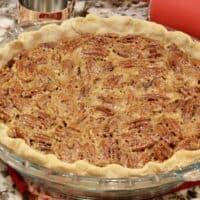 Whole bourbon pecan pie with rolling pin behind it.