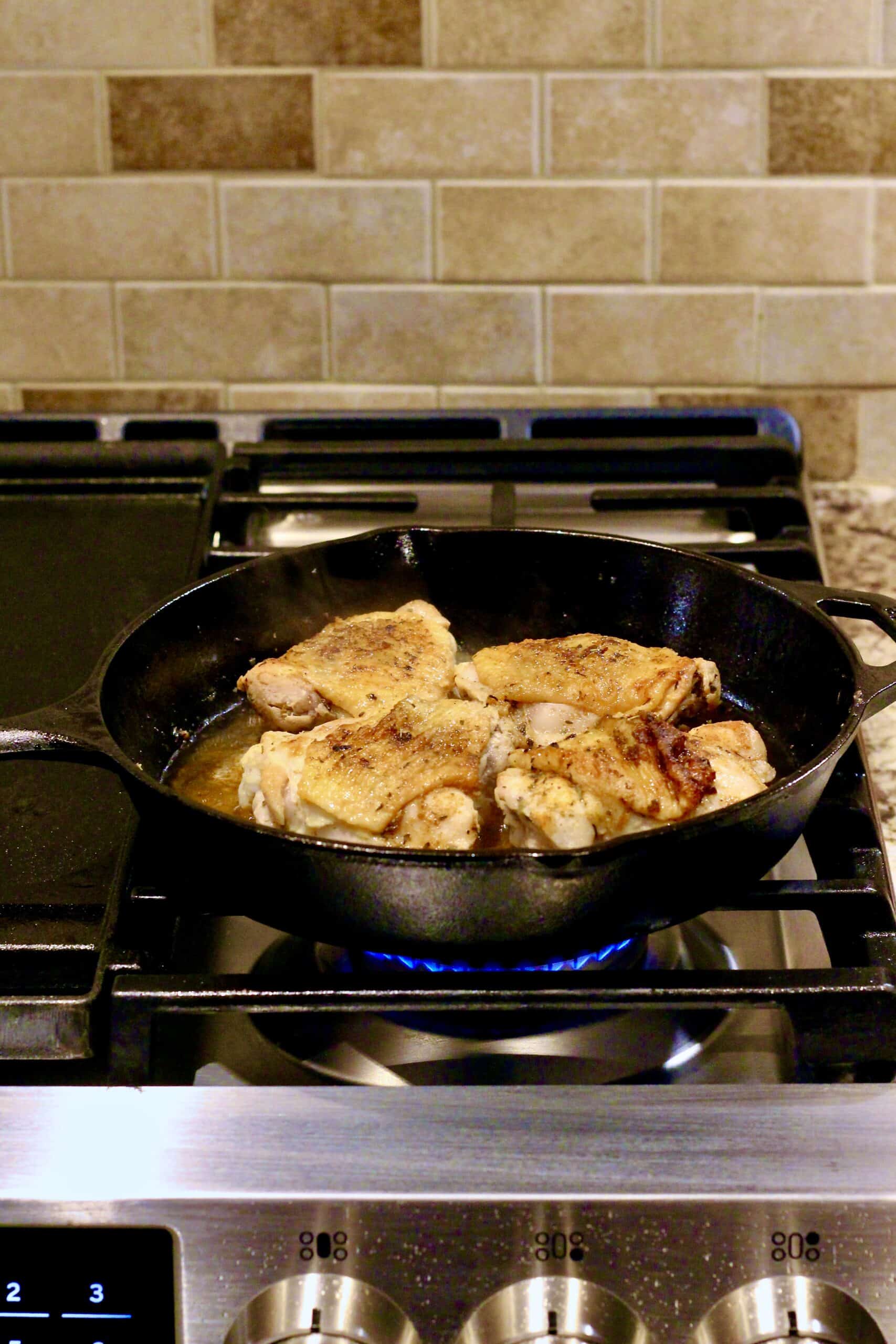 Frying chicken in a cast iron pan over a gas flame.