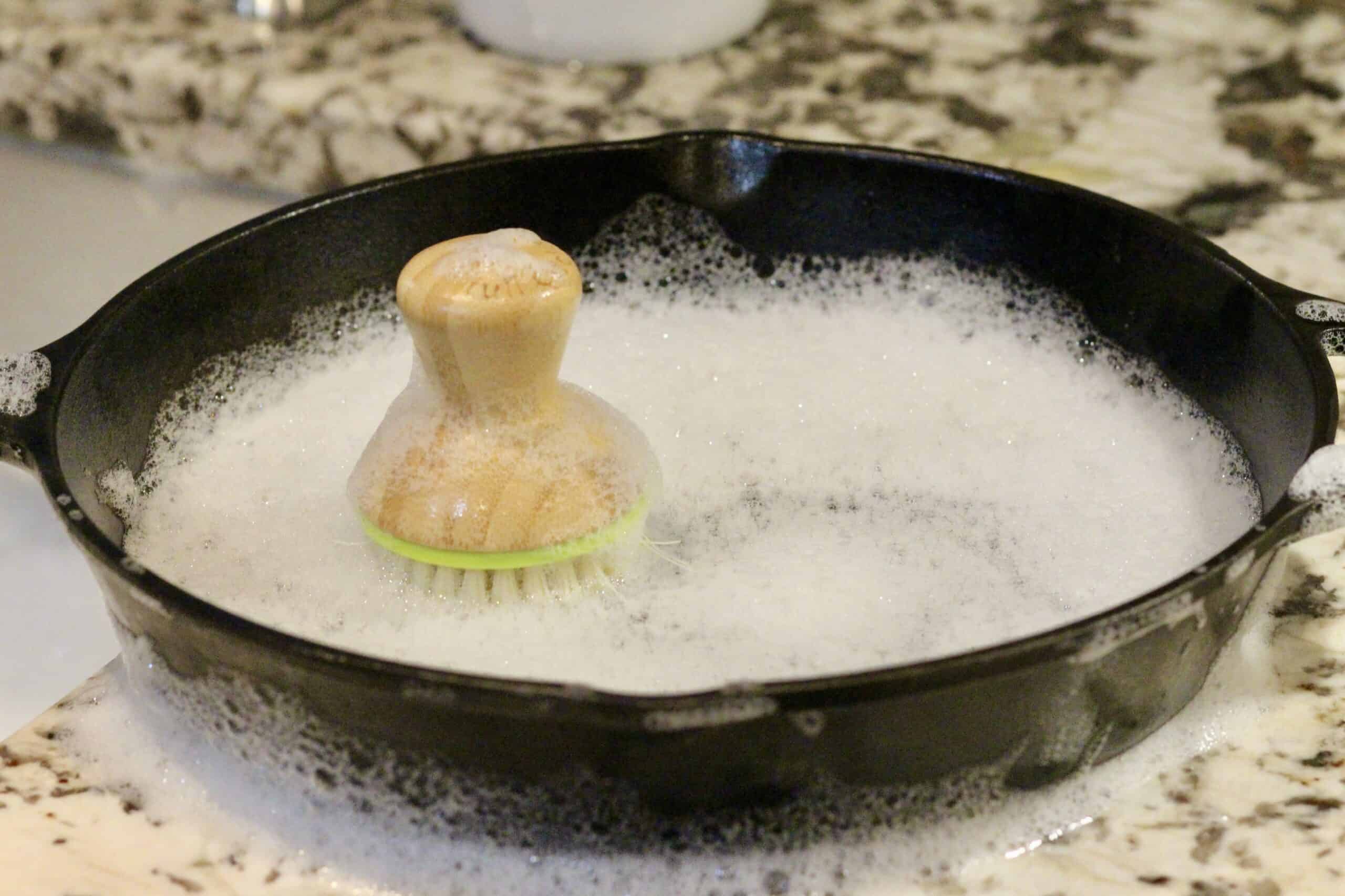A wood handled brush inside a cast iron skillet.