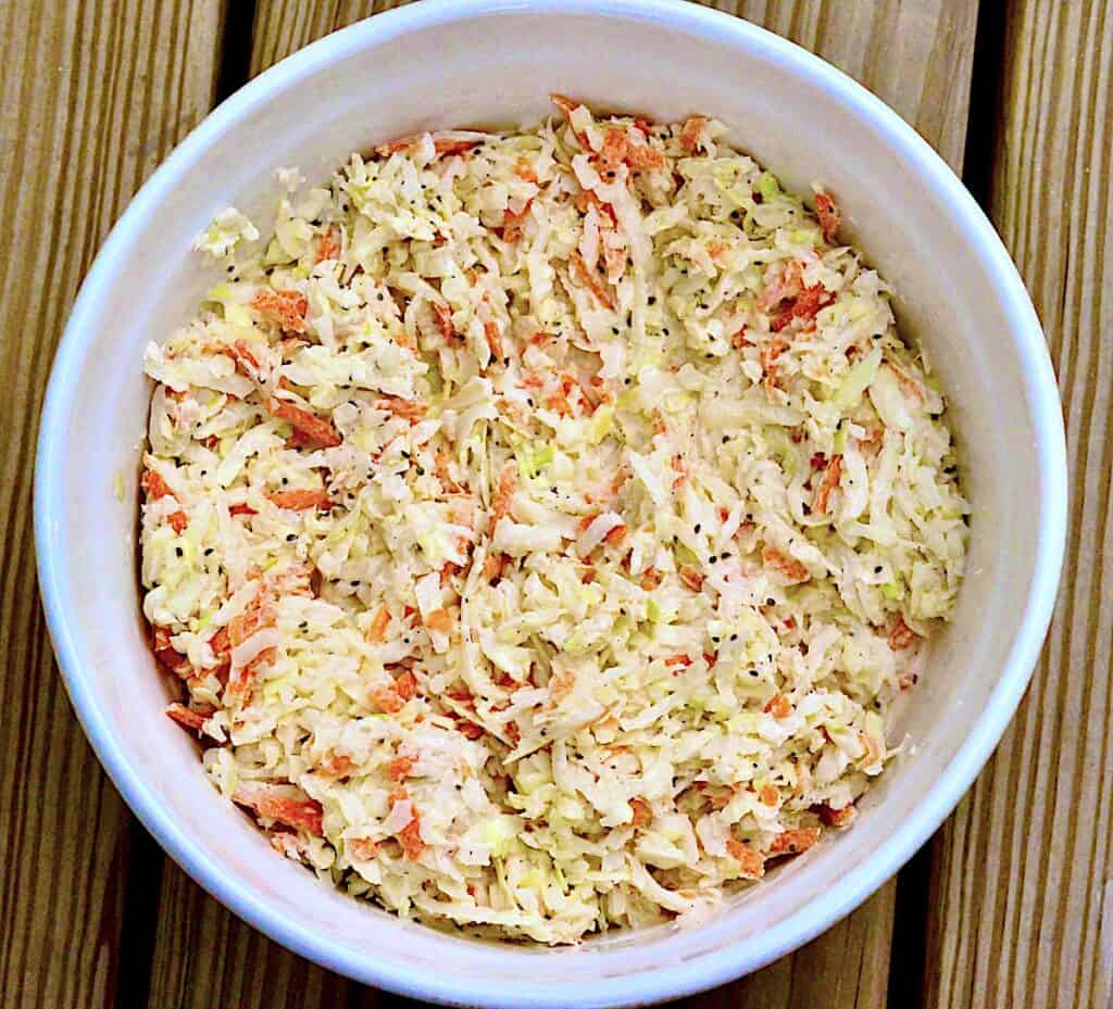 Bowl of coleslaw on wooden boards.