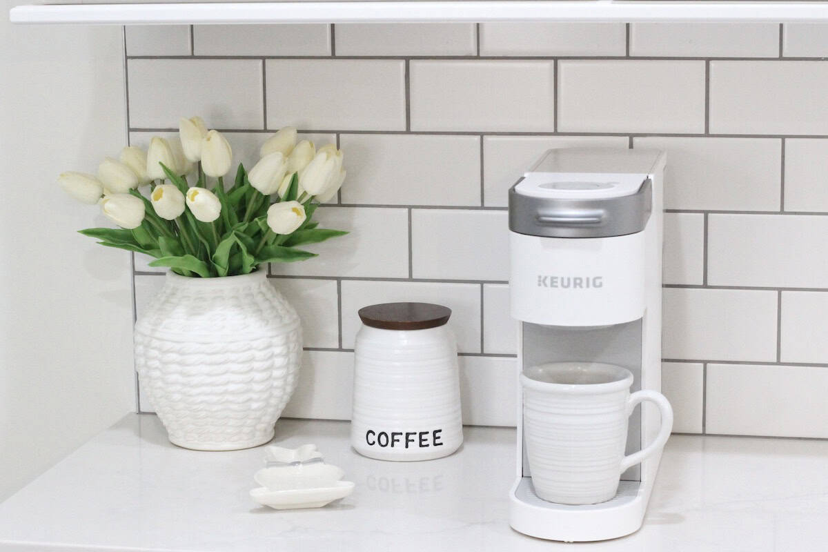 Keurig coffee maker with coffee container and a vase of tulips.