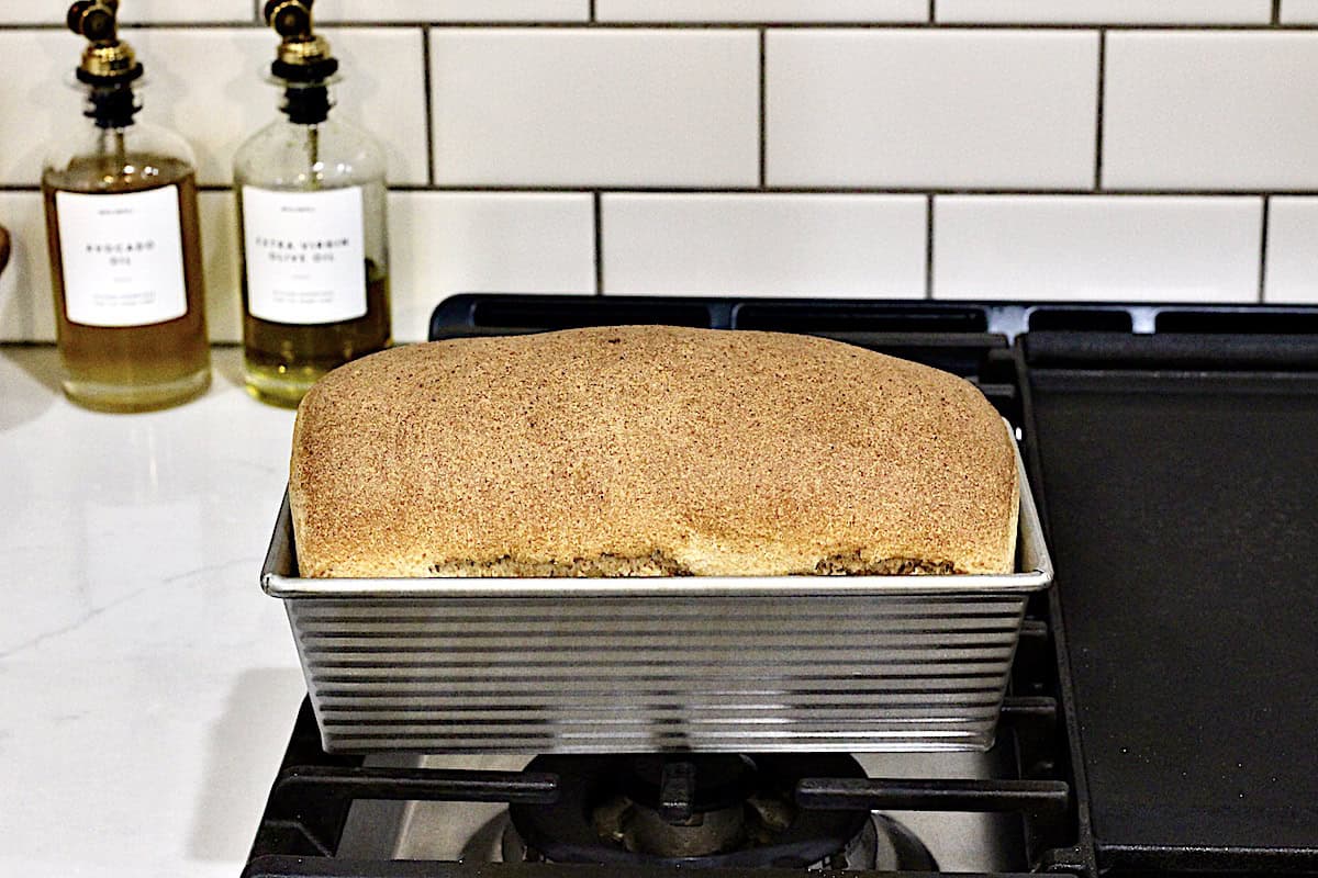 A bread loaf in a metal pan on a stove top.