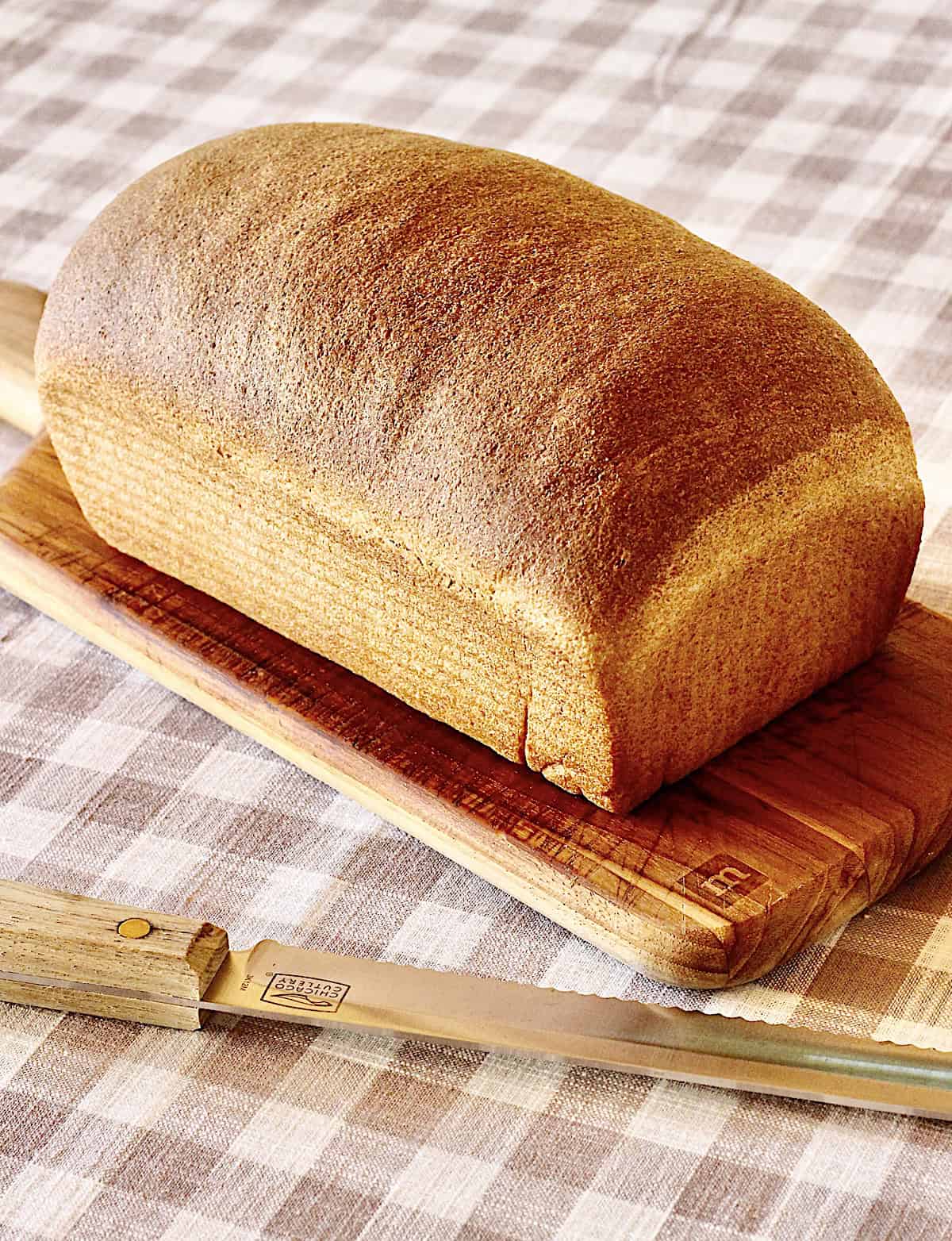 Baked bread on a cutting board with a bread knife beside it.