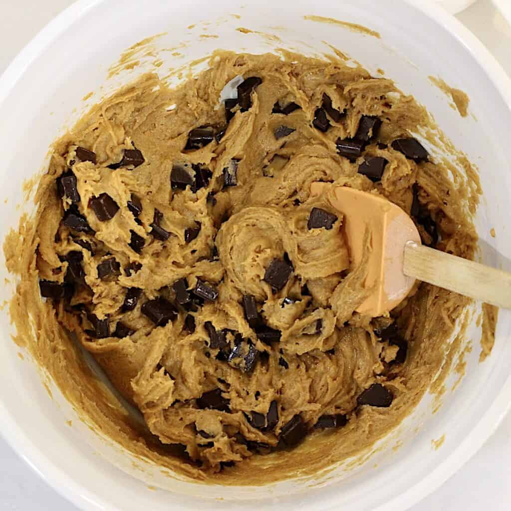 Pumpkin chocolate chunk cookie batter in a bowl with a spoon.