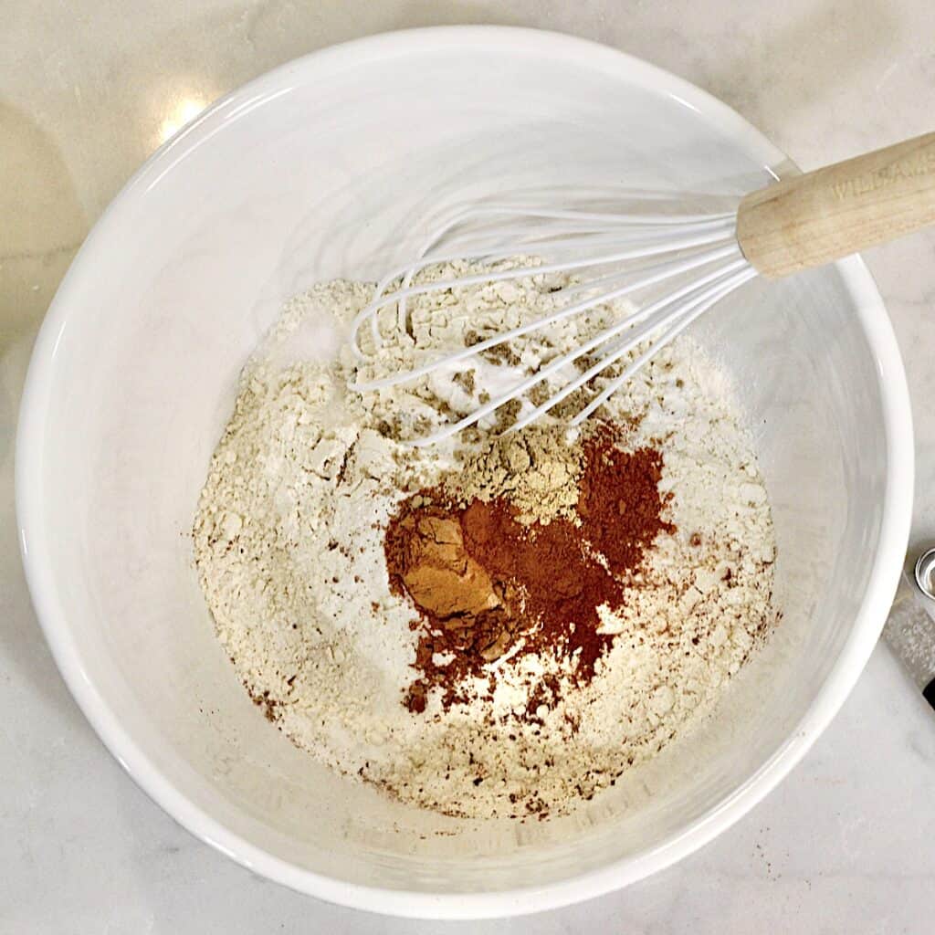 A whisk in a bowl filled with flour and spices.