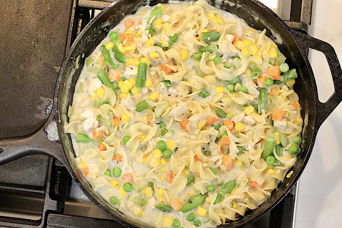 Turkey noodle casserole cooking in a cast iron skillet.