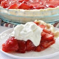 A slice of strawberry pie next to a whole strawberry pie.